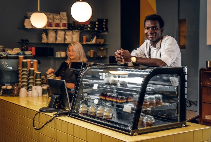 Two young multiracial baristas working at their trendy coffee shop.