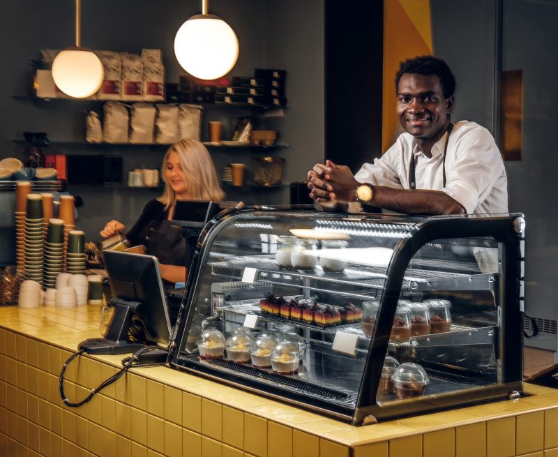 Two young multiracial baristas working at their trendy coffee shop.